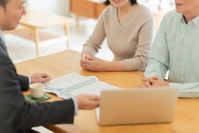 中年夫婦に説明するビジネスマン