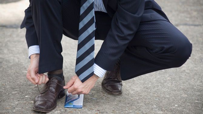 ほどけた靴紐を結ぶスーツの男性