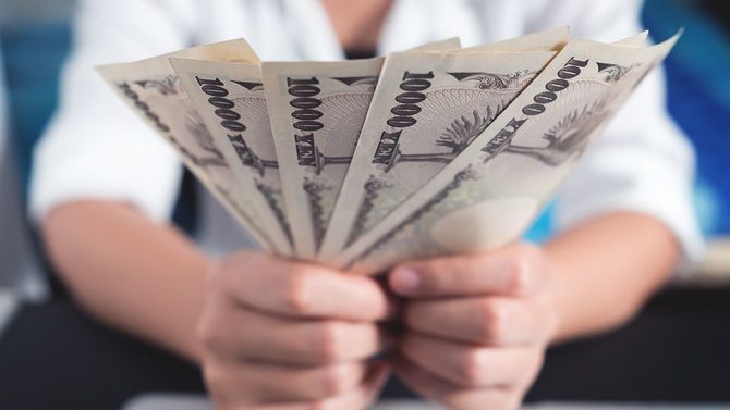 数枚の一万円札を持つ手元