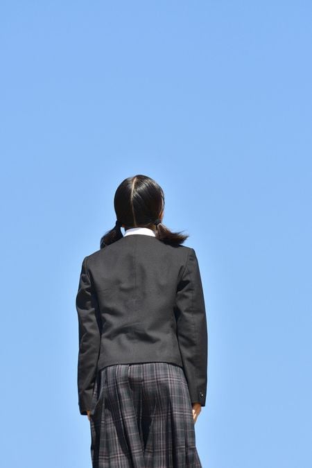 青空の背景に立っている制服の女の子