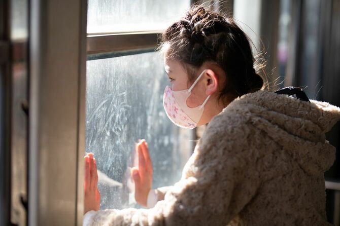マスクをして窓の外を見ている女の子