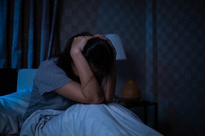 ベッドで頭を抱える女性