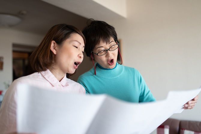 歌の練習をする、シニア女性と中年女性
