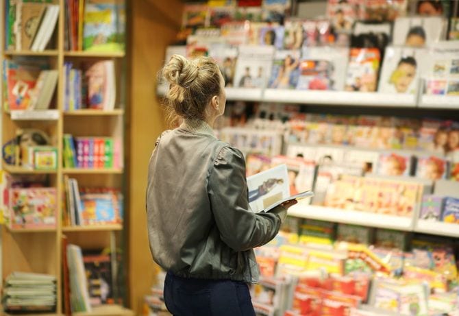 書店の雑誌の棚を見つめる女性