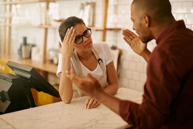 喫茶店で顧客のクレームに対応する若い女性