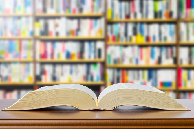 図書館の低い書棚の上に、開いて置かれた分厚い書物