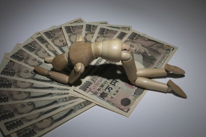 たくさんの一万円札の上で慟哭するデッサン人形