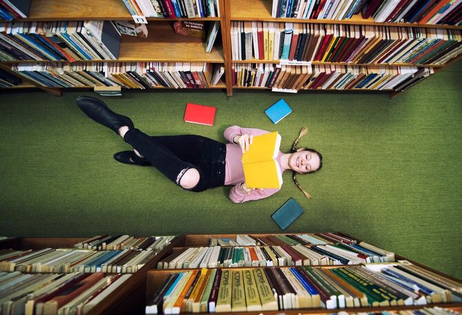 読書をしながら横たわる学生