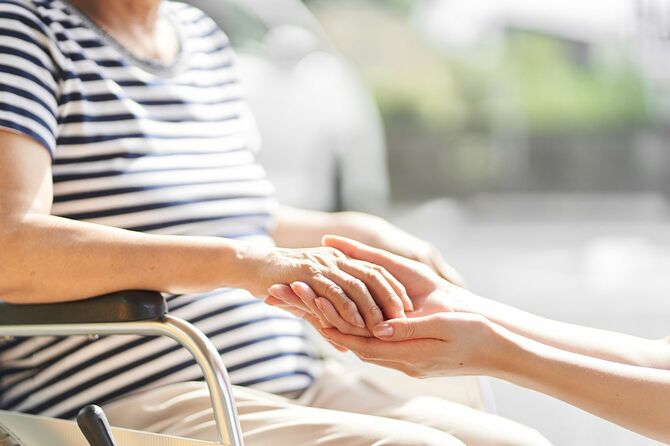 車椅子の介護者と高齢者の手