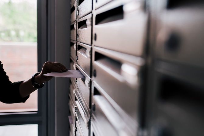 郵便受けに封筒を入れる人