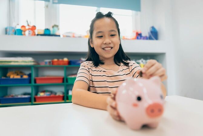 貯金箱にお金を入れる子ども
