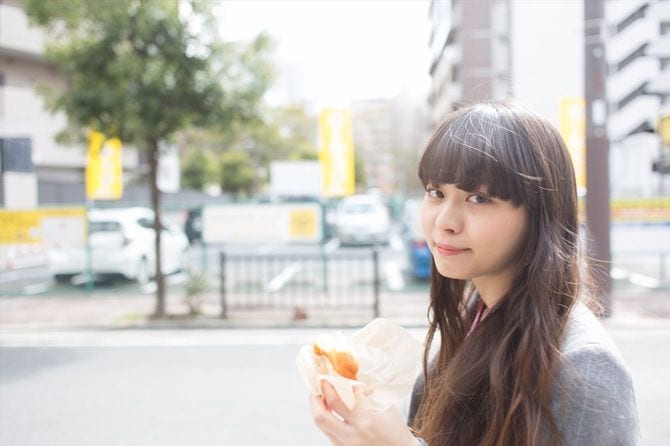 歩きながらドーナツを食べている女性