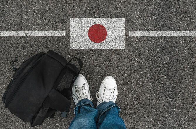 道路に描かれた日本の国旗の前に立つ人