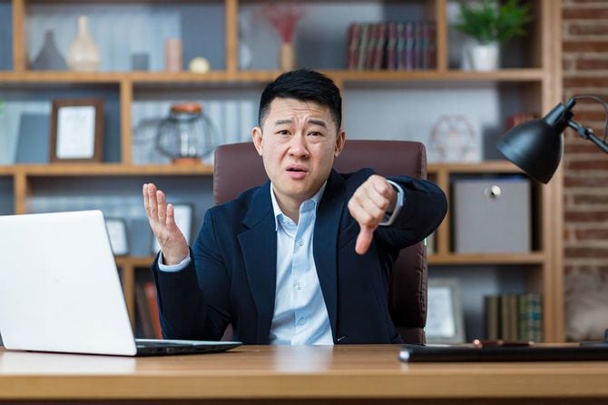 親指を下に向けていら立つ男性