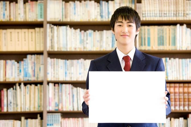 図書館でメッセージボードを持つ男子生徒