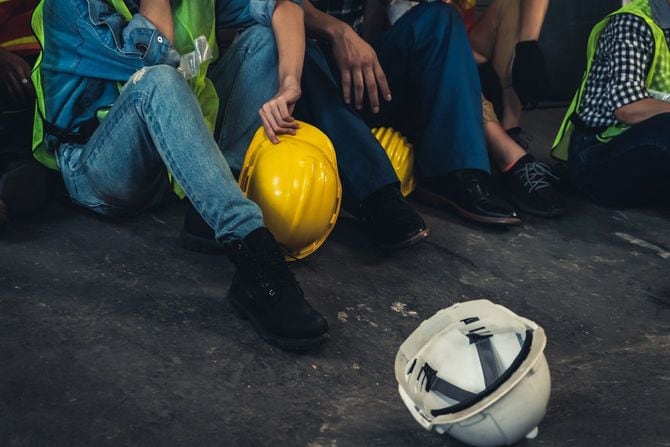 床に座り込み、ヘルメットを脱いで休んでいる作業員たち