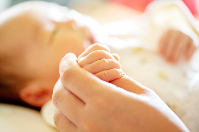 生まれたばかりの赤ちゃんの手を握る親の手