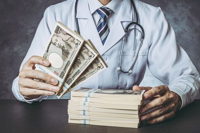 お金の札束を持つ男性医師