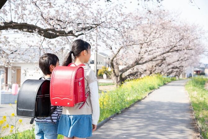 桜が咲く小路に立つ二人の小学生