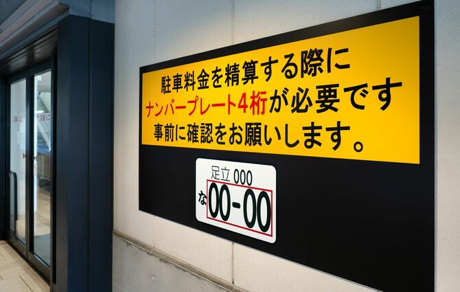 駐車料金を精算する際にナンバープレート4桁が必要になる旨が掲示されている駐車場
