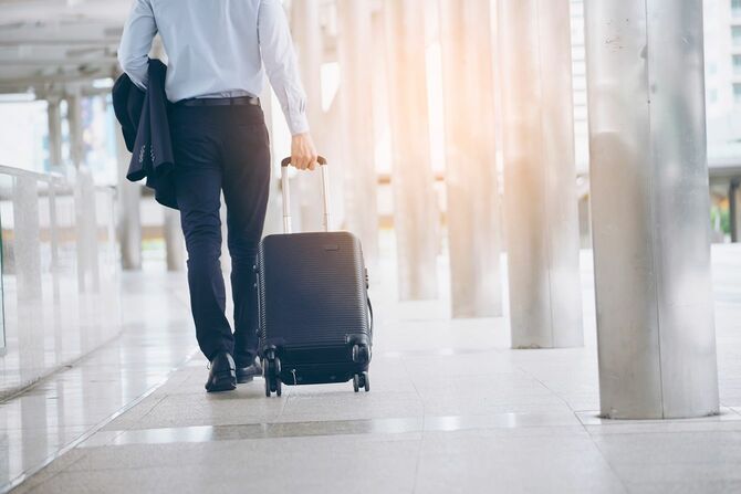 スーツケースを引くスーツの男性