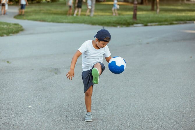 少年はサッカーボールで遊ぶ