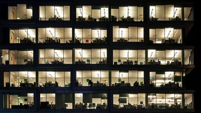 明かりがついたオフィスで仕事をする人々