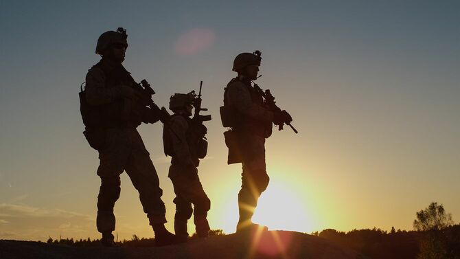 光夕日の砂漠環境での丘の上に立っている 3 つの完全装備と武装兵士の分隊