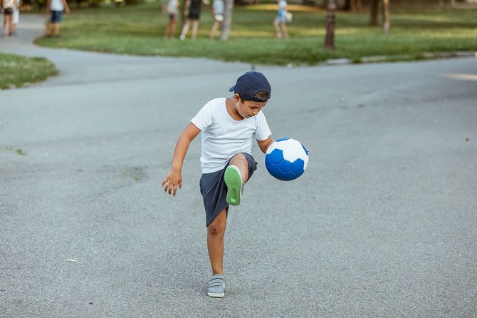 少年はサッカーボールで遊ぶ