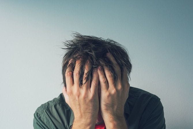 頭を抱えて嘆いている男性