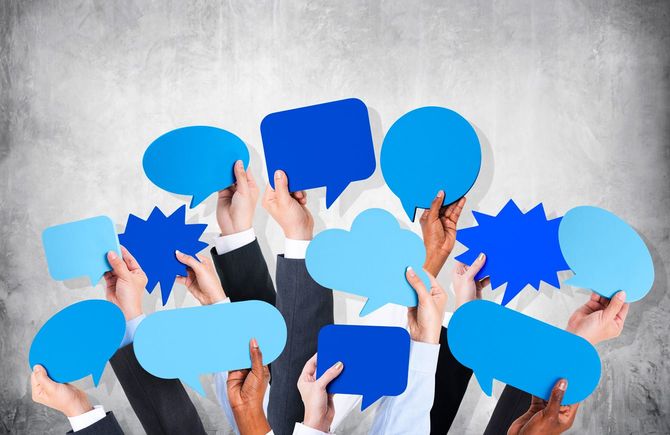 吹き出しを掲げるビジネスパーソンたちの腕