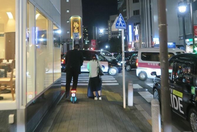 夜、繁華街の歩道を走るLUUP