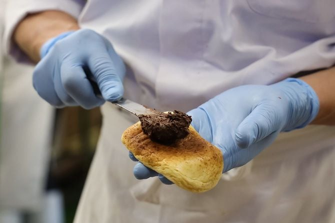 職人の手でブラックサンダー入りのチョコレートクリームを巻いていく