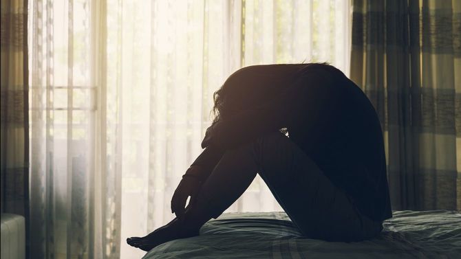 ベッドに座り込んでうつ病に苦しむ女性