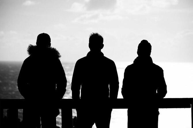 手すりの前に立っている3人の後ろ姿のシルエット