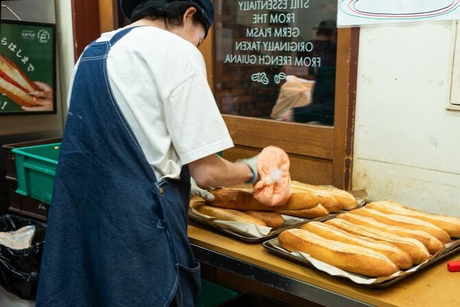 明太バターのフィリングをフランスパンに絞っているスタッフ