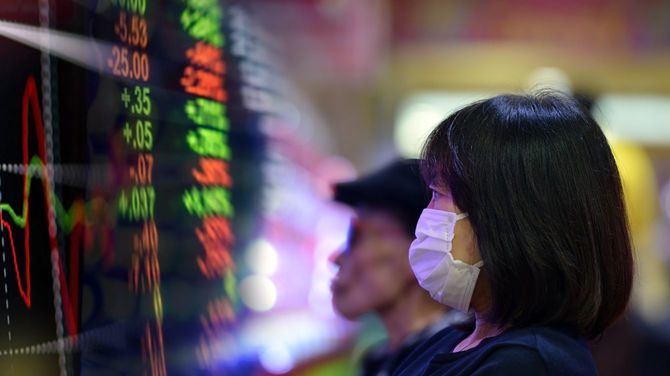 マスクを着けて株価ボードを見つめる女性