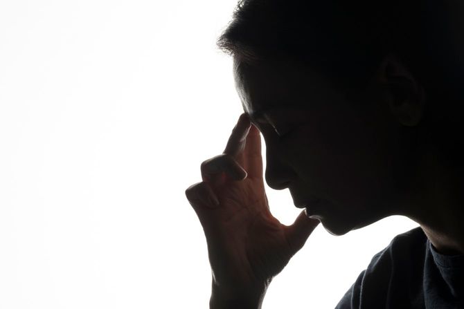 こめかみを押さえる女性のシルエット