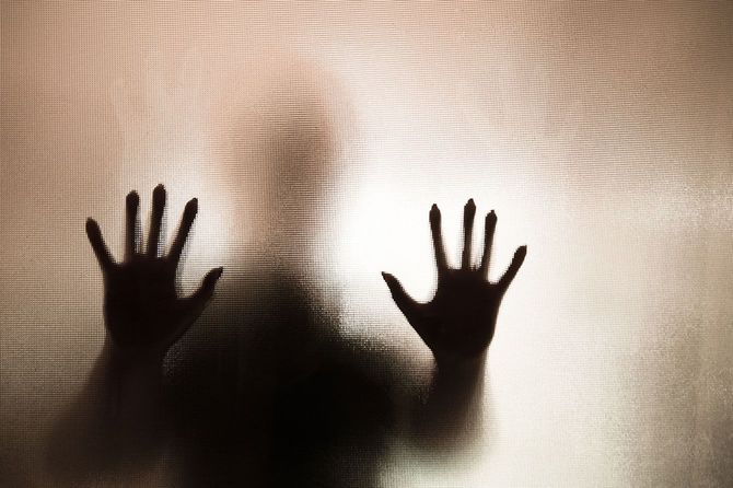 すりガラス越しに手を押し付けた人のシルエット