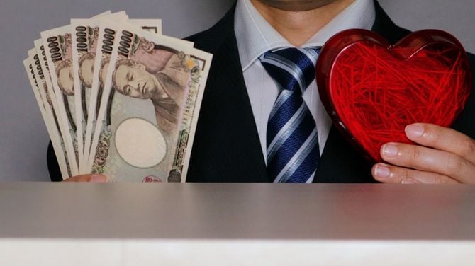 紙幣とハートを持つビジネスマン