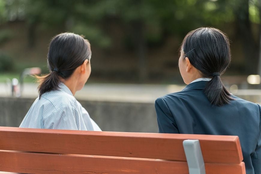 教師と生徒が公園のベンチで話している