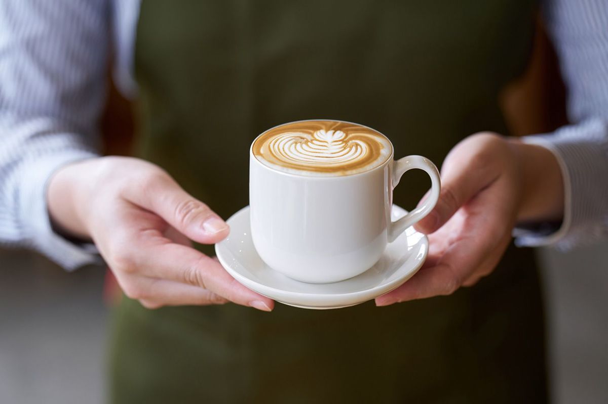 コーヒーを提供するカフェ店員