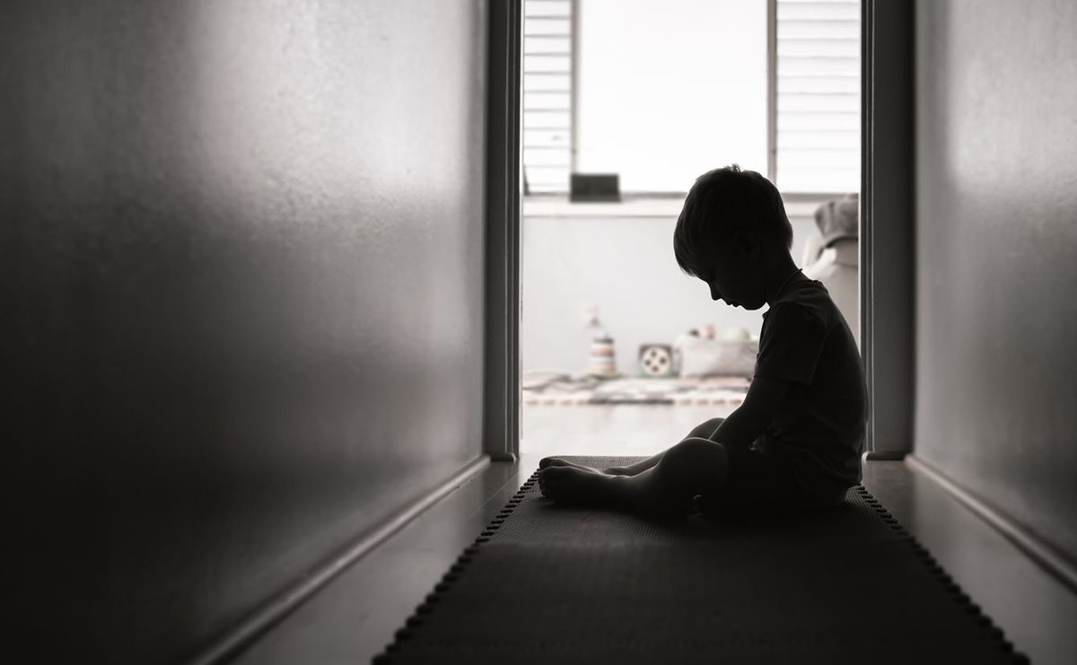家の廊下に一人で座る悲しい少年