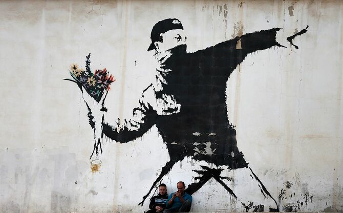 バンクシーの「花束を投げる人」（ヨルダン川西岸ベツレヘム）＝2015年12月16日