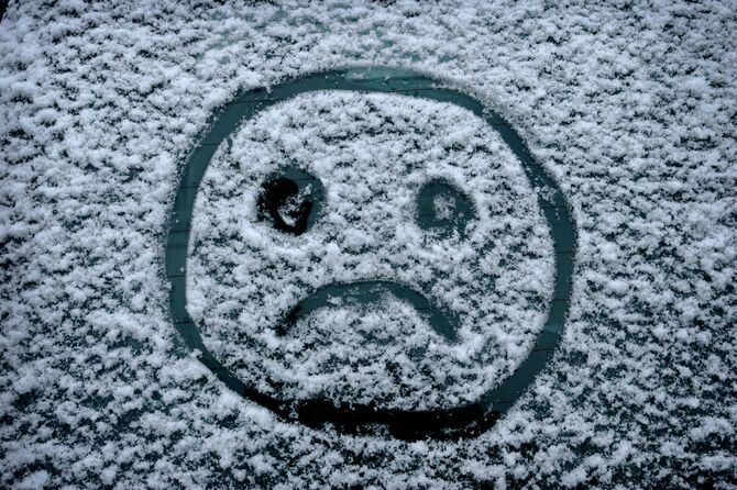 うっすら積もった雪に描かれた悲しい顔のマーク