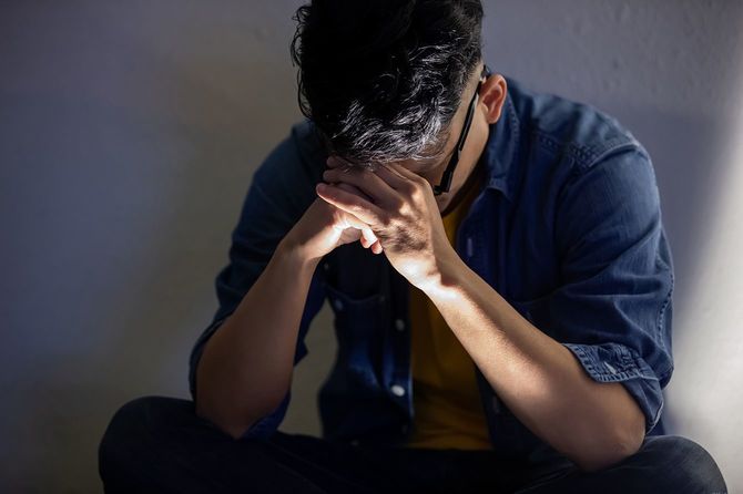 アジアの男は何かについて動揺し、夕方に屋外に座って