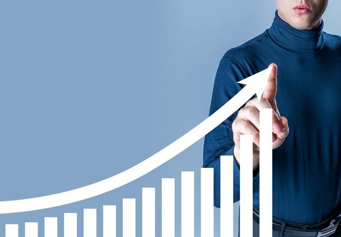 右肩上がりのグラフが描く上向き矢印を指す男性