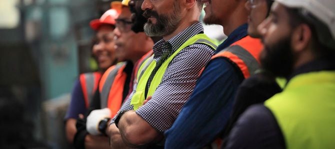 腕を組んで並び立つ工場労働者たち