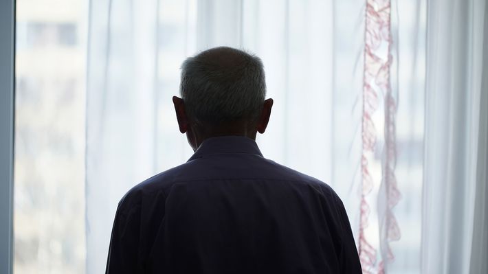 窓の外を眺めるシニア男性