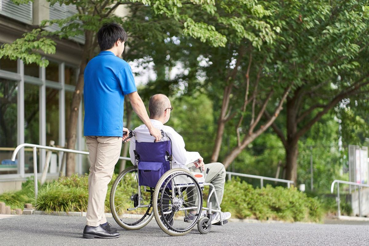 車椅子の高齢者をサポートする介護者